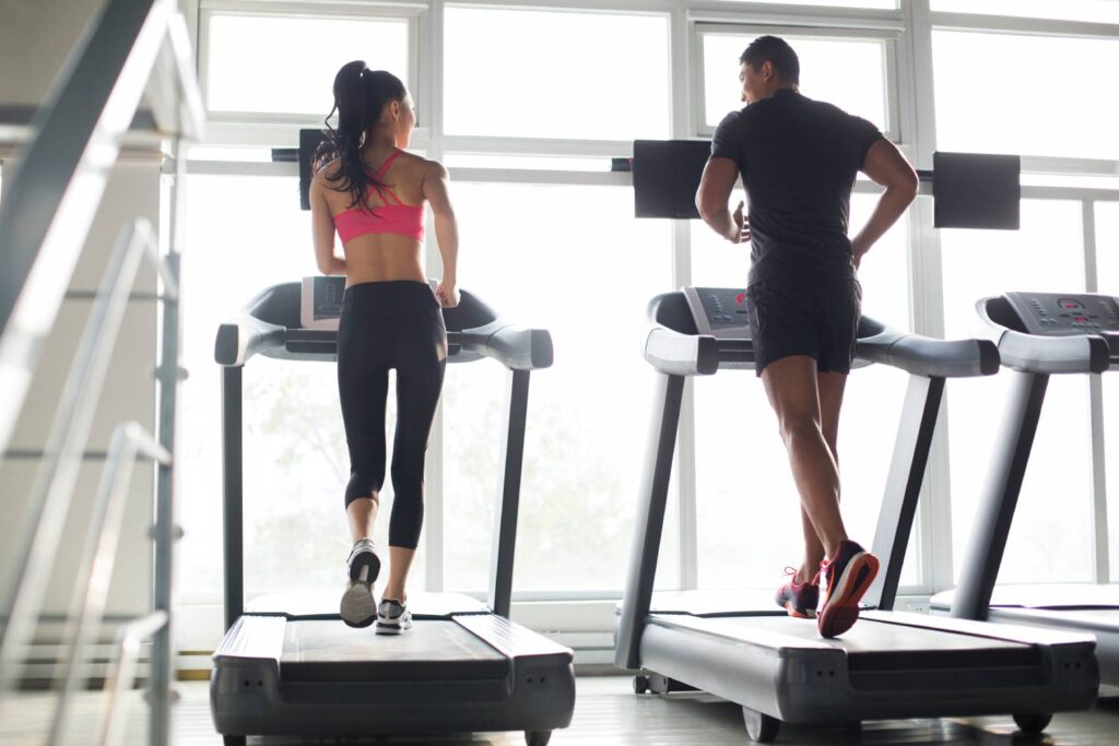 Young Chinese couple exercising on treadmills in gym